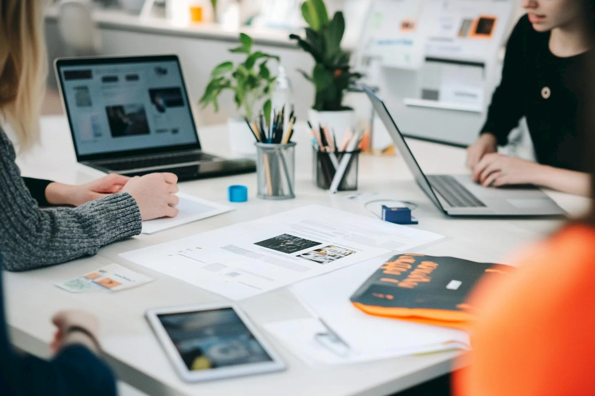 Zespół omawiający projekt strony internetowej przy laptopie i materiałach projektowych